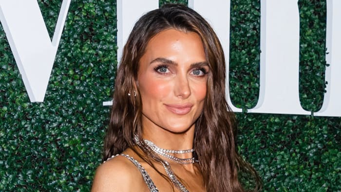 Melissa Wood-Tepperberg poses in a sequined top and necklaces and smiles for the camera.